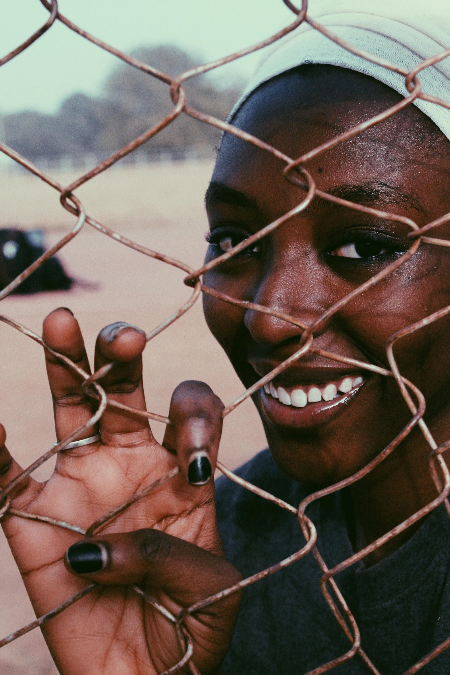 a close up of a person behind a fence, smiling playfully, in africa, instagram picture, film still