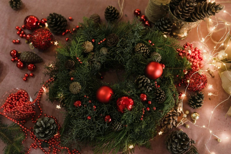 a wreath sitting on top of a table covered in christmas decorations, pexels, hurufiyya, gradient brown to red, evergreen, frontal shot, modeled