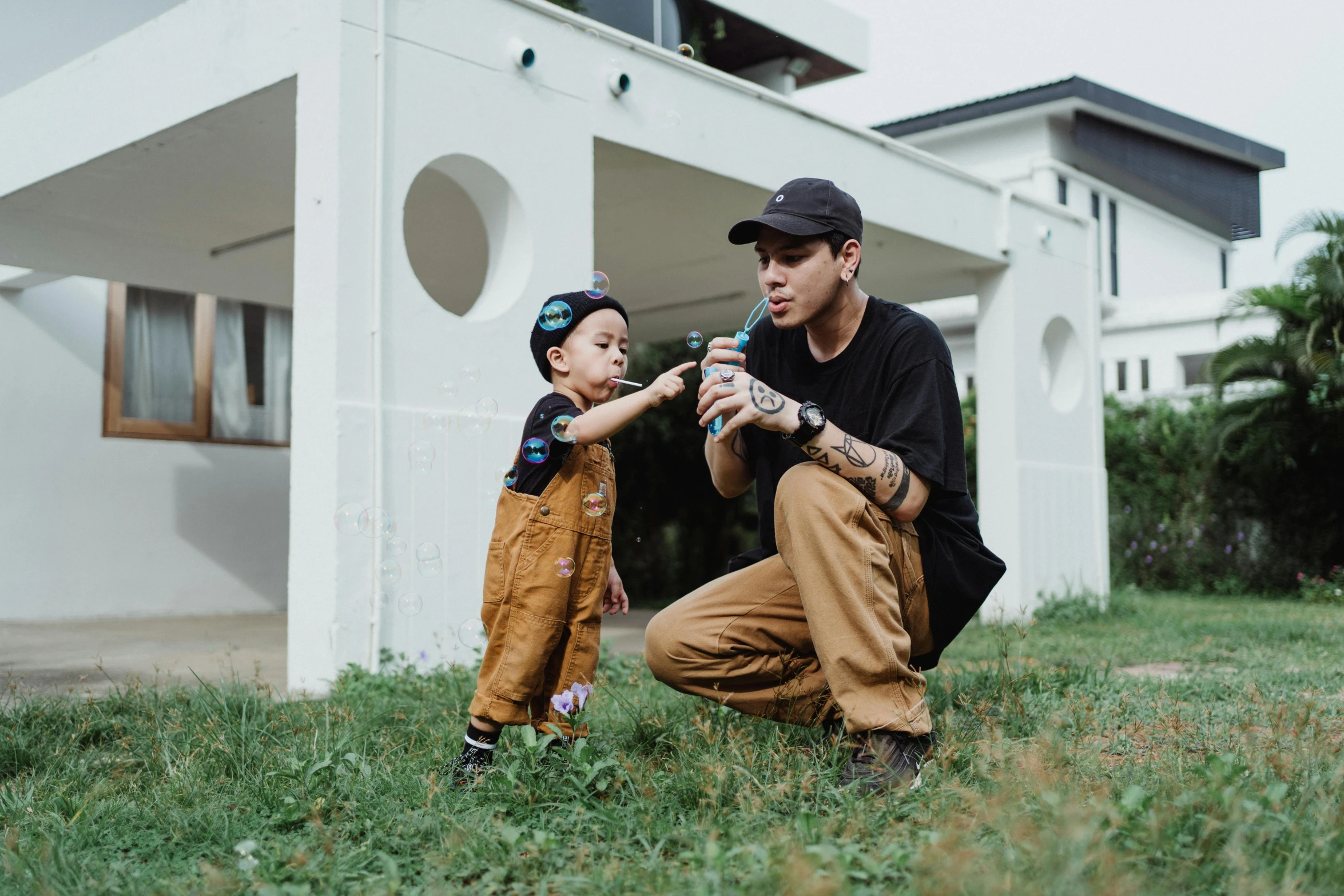 a man kneeling down next to a little boy, pexels contest winner, graffiti, kenny wong x pop mart, khakis, in garden, avatar image