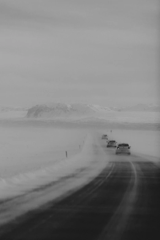 a couple of cars driving down a snow covered road, a black and white photo, by Þórarinn B. Þorláksson, conceptual art, antarctic, ffffound, dust storm, (3 are winter