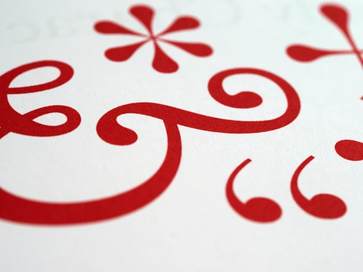 a close up of a red design on a piece of paper, inspired by Zsolt Bodoni, behance, letterism, swirly curls, peppermint motif, handcrafted, animation