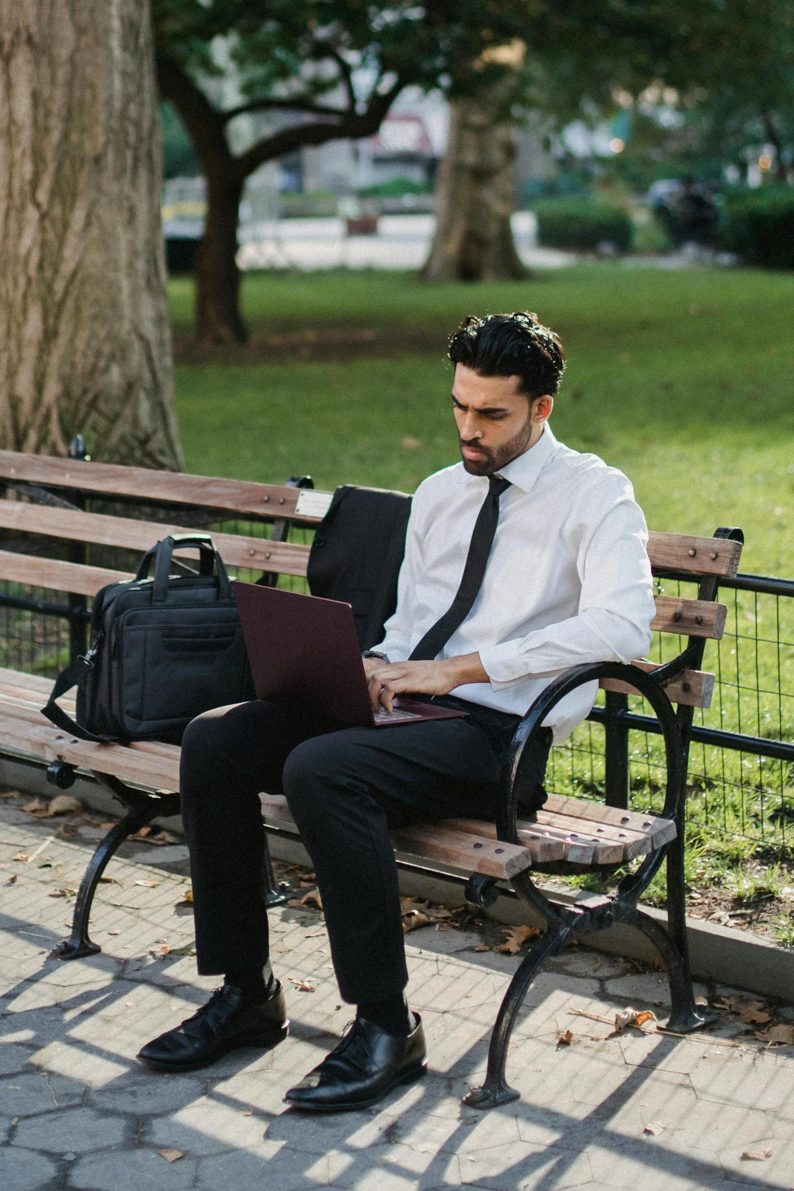 a man sitting on a bench with a laptop, white dress shirt, he is carrying a black briefcase, 2019 trending photo, parks