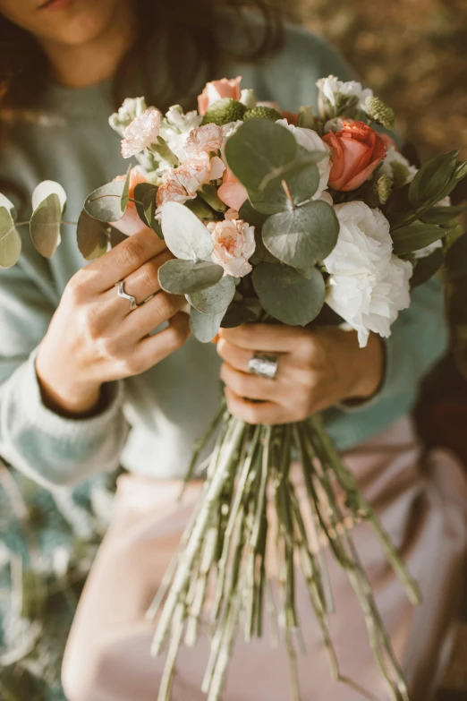 a woman holding a bunch of flowers in her hands, by Adriaen Hanneman, trending on unsplash, romanticism, engagement ring ads, silver filigree details, eucalyptus, detail shot