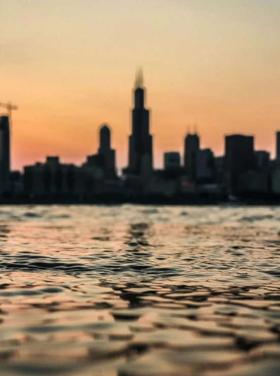 a large body of water with a city in the background, by Greg Rutkowski, pexels contest winner, golden hour closeup photo, from wheaton illinois, the photo was taken from a boat, blurred photo