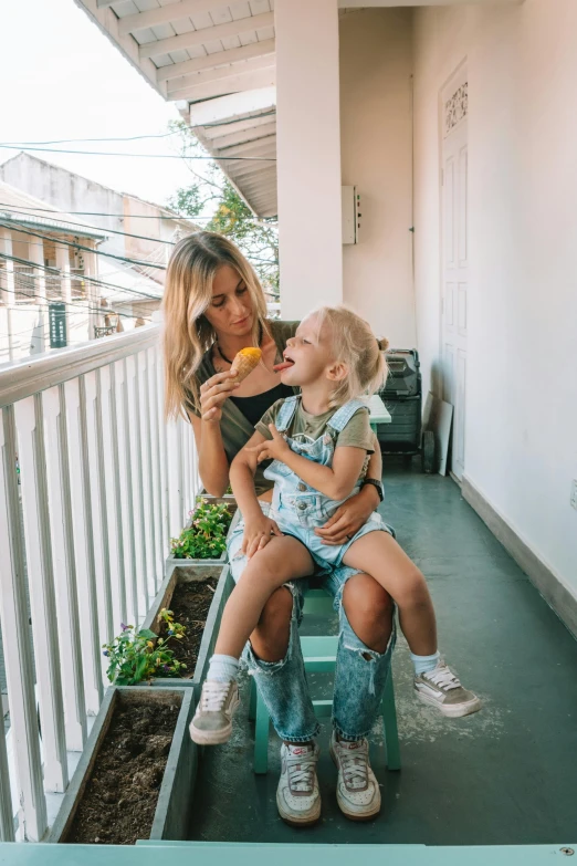 a woman holding a child on a balcony, pexels contest winner, blond hair with pigtails, brazil, instagram photo, denim