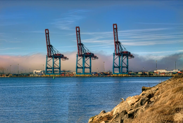 a group of cranes sitting on top of a body of water, a tilt shift photo, pexels contest winner, shipping docks, vallejo, three towers, hdr on