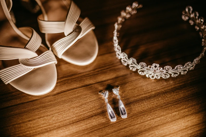 a pair of shoes and a necklace on a table, pexels contest winner, diadems, silver，ivory, thumbnail, a wooden