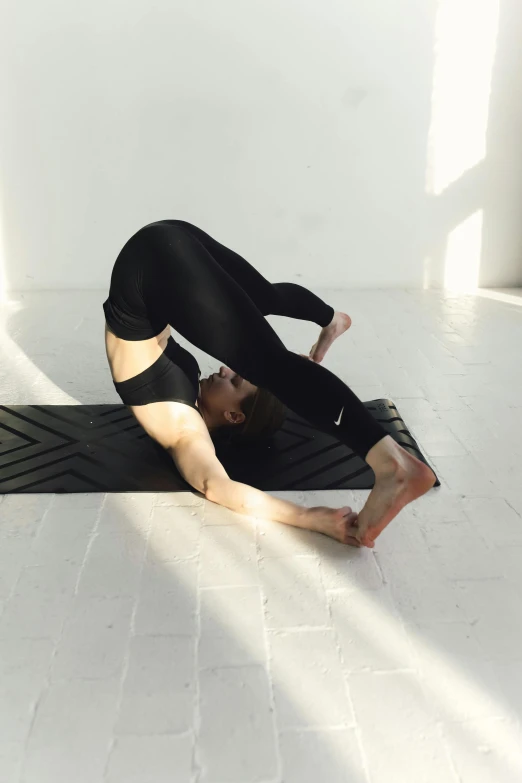 a woman doing a yoga pose on the floor, pexels contest winner, arabesque, back arched, black spandex, promo image, square