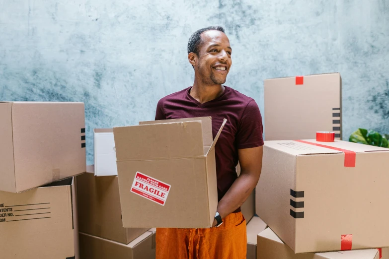 a man standing in front of a pile of boxes, pexels contest winner, renaissance, brown skin man with a giant grin, leaving a room, listing image, maintenance photo