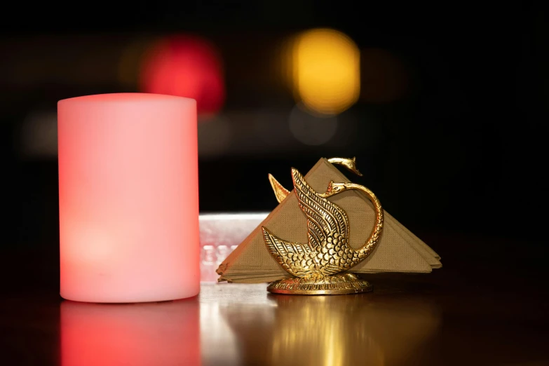 a candle that is sitting on a table, hurufiyya, swan, golden pyramids, dim accent lighting, the flamingo cafe