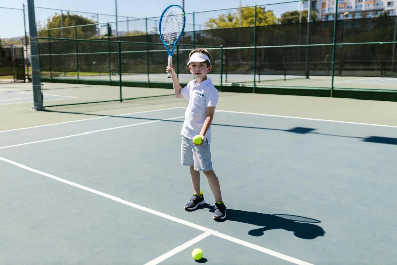 a young boy holding a tennis racquet on a tennis court, a portrait, by Dan Content, pexels contest winner, sunny day time, thumbnail, full body image, 5 years old