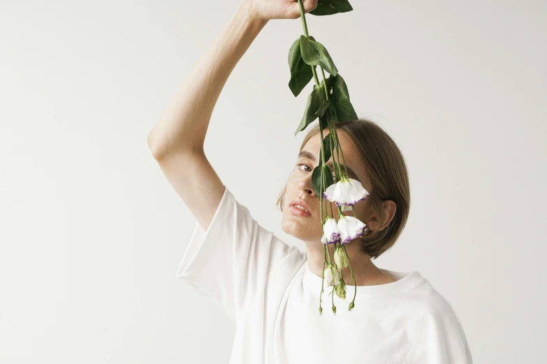 a woman holding a bunch of flowers above her head, inspired by Anna Füssli, trending on pexels, aestheticism, man in white t - shirt, ikebana, thin young male alchemist, photoshoot for skincare brand