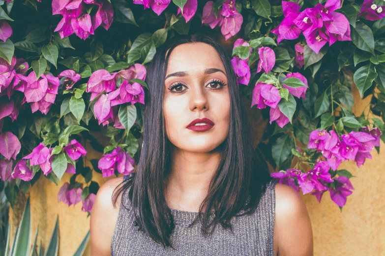 a woman standing in front of a bunch of flowers, an album cover, pexels contest winner, hurufiyya, purple lipstick, indian girl with brown skin, perfect silky straight hair, relaxed eyebrows