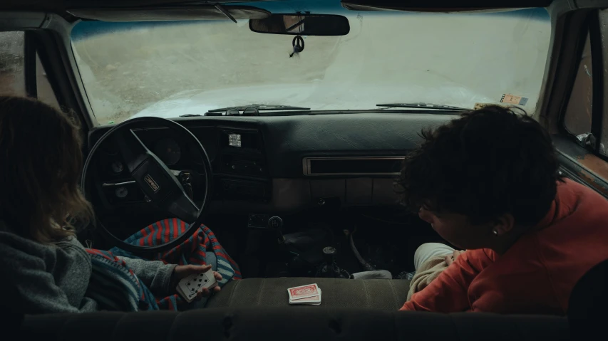 a couple of people that are sitting in a car, by Elsa Bleda, pexels contest winner, holds playing cards, teenage boy, square, cinematic wide shot