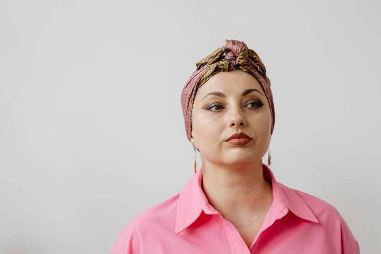 a woman wearing a pink shirt and a turban, by Emma Andijewska, trending on pexels, hurufiyya, wearing a head scarf, sydney hanson, plus-sized, tumours