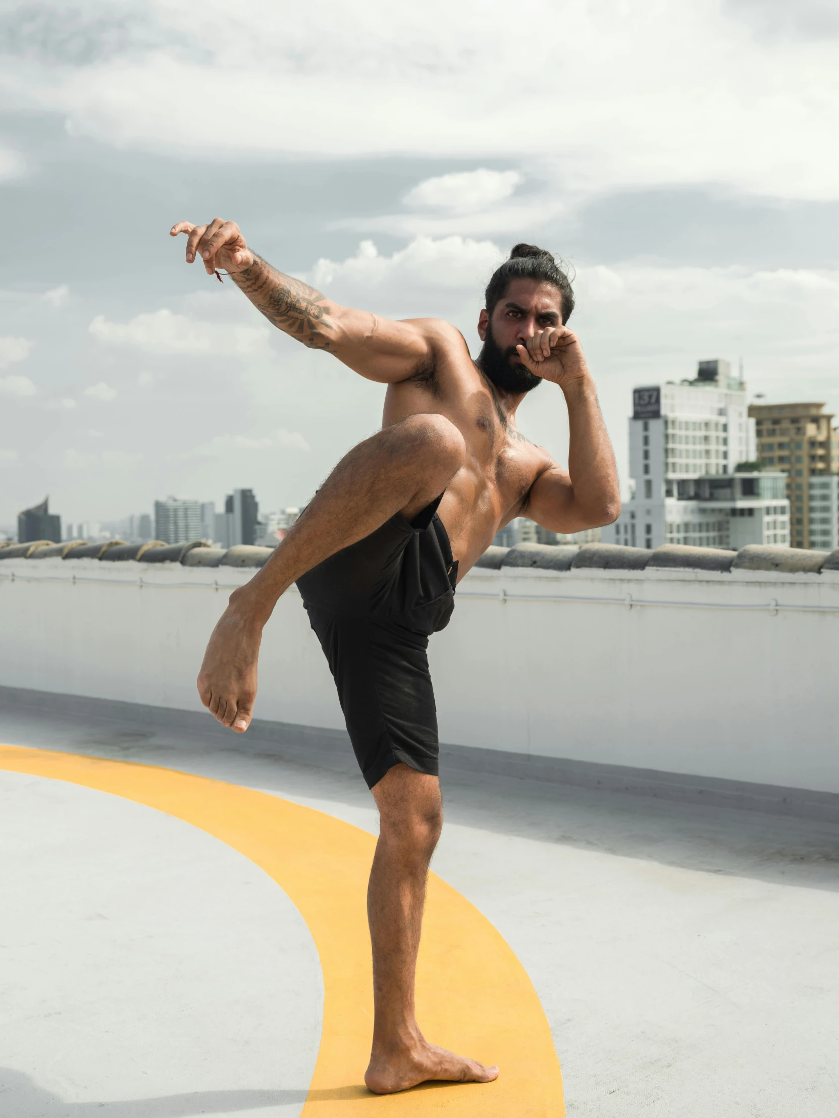 a man doing a kick on the roof of a building, a tattoo, by Jessie Alexandra Dick, pexels contest winner, heroic muay thai stance pose, a portrait of rahul kohli, wearing black shorts, snapchat photo