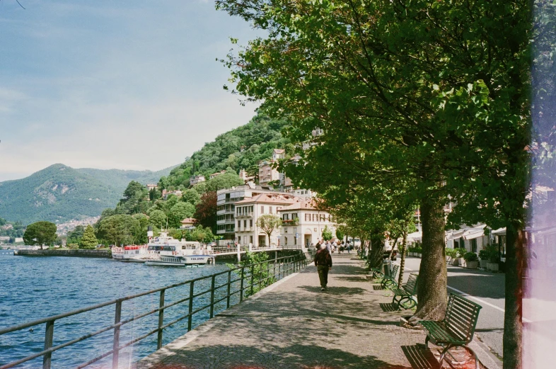 a couple of benches sitting next to a body of water, pexels contest winner, running through italian town, lo fi, joel meyerowitz, river and trees and hills