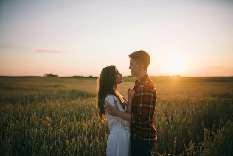 a man and woman standing in a field at sunset, pexels contest winner, attractive girl, sydney hanson, plain background, a single