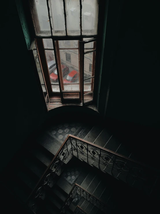 a staircase leading up to a window in a dark room, looking down on the camera, large open windows, overlooking a dark street, gloomy library