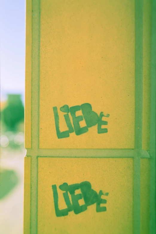a close up of graffiti on the side of a building, inspired by Wilhelm Leibl, unsplash, greenish expired film, love hate love, on yellow paper, monument