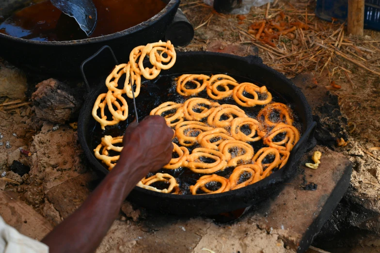 a person that is cooking some kind of food, trending on pexels, hurufiyya, made of wrought iron, rondel, unmistakably kenyan, lots of swirling