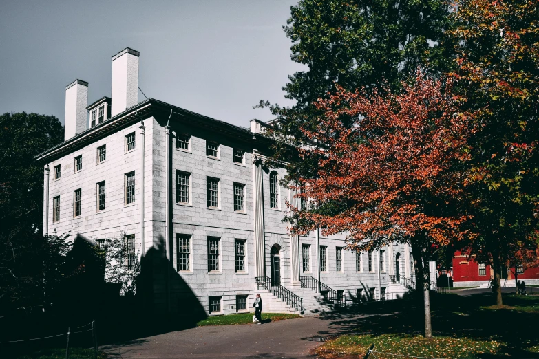 a large white building sitting on top of a lush green field, unsplash, vancouver school, autumnal, lomography lady grey, with dark trees in foreground, halls