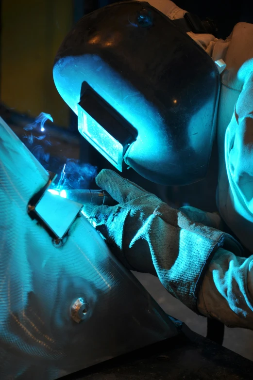 a welder working on a piece of metal, by Tom Bonson, glowing cyan blue plasma, thumbnail, worn, university