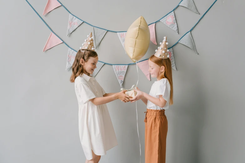 two little girls standing next to each other holding balloons, pexels contest winner, aestheticism, crown made of fabric, brown and white color scheme, on a canva, decoration