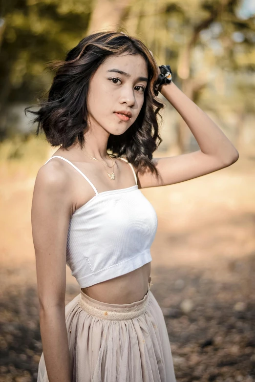 a woman in a skirt posing for a picture, by Reuben Tam, trending on pexels, white halter top, 🤤 girl portrait, croptop, soft morning lighting