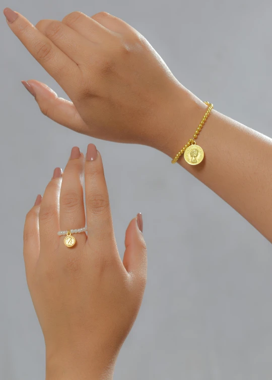 a close up of two hands with rings on them, coin with the letter n, wearing gold jewellery, in style of lam manh, mini model