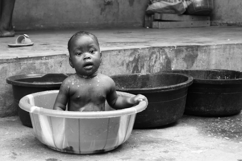 a black and white photo of a baby in a tub, a black and white photo, by Chinwe Chukwuogo-Roy, black & white photo, street photo, photo of a beautiful, christian