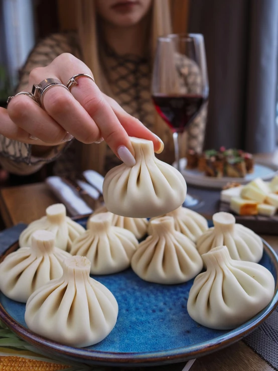 a woman sitting at a table with a plate of dim dim dim dim dim dim dim dim dim dim dim dim dim dim dim dim dim dim, reddit, hurufiyya, dumplings on a plate, holding khopesh, plenty mozzarella, 🎀 🧟 🍓 🧚