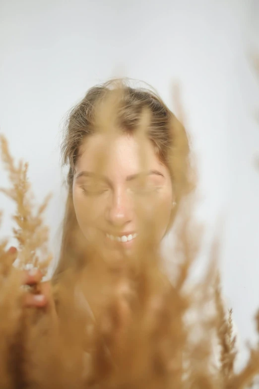 a woman standing in a field of tall grass, pexels contest winner, conceptual art, blurred face, photoshoot for skincare brand, set against a white background, relaxed. gold background