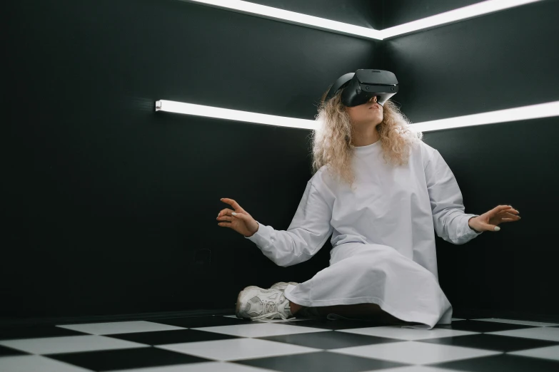 a woman sitting on a checkered floor wearing a virtual reality headset, unsplash contest winner, interactive art, wearing a white robe, futuristic clothing and helmet, indie games, healthcare