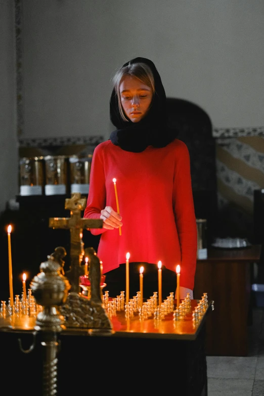 a woman standing in front of a table with candles, orthodoxy, filmstill, concentration, high quality image