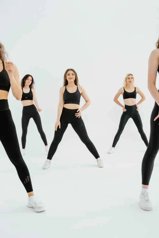 a woman standing in front of a group of other women, trending on pexels, arabesque, jet black leggins, textured base ; product photos, origin jumpworks, panoramic