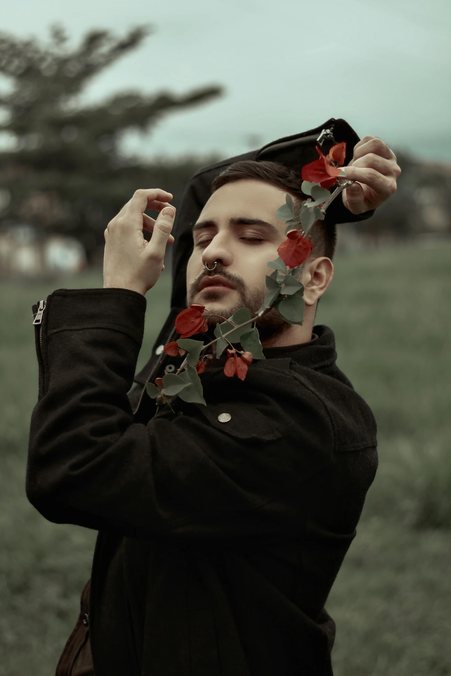 a man standing on top of a lush green field, a colorized photo, inspired by Elsa Bleda, pexels contest winner, aestheticism, black roses in hair, handsome face, red selective coloring, made of leaves