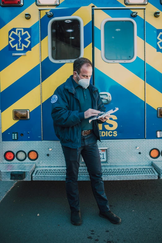 a man in a face mask standing in front of an ambulance, a photo, by Meredith Dillman, pexels, inspect in inventory image, blue, natgeo, full body profile