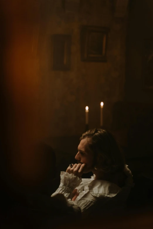 a woman sitting on a couch in a dark room, inspired by Godfried Schalcken, pexels, rococo, beautiful man, candles. baroque elements, ✨🕌🌙, movie scene close up