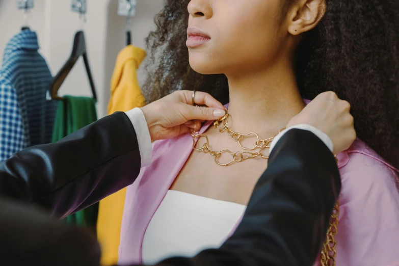 a woman putting a necklace on another woman's neck, trending on pexels, tailored clothing, wearing a royal robe, portrait of vanessa morgan, thumbnail