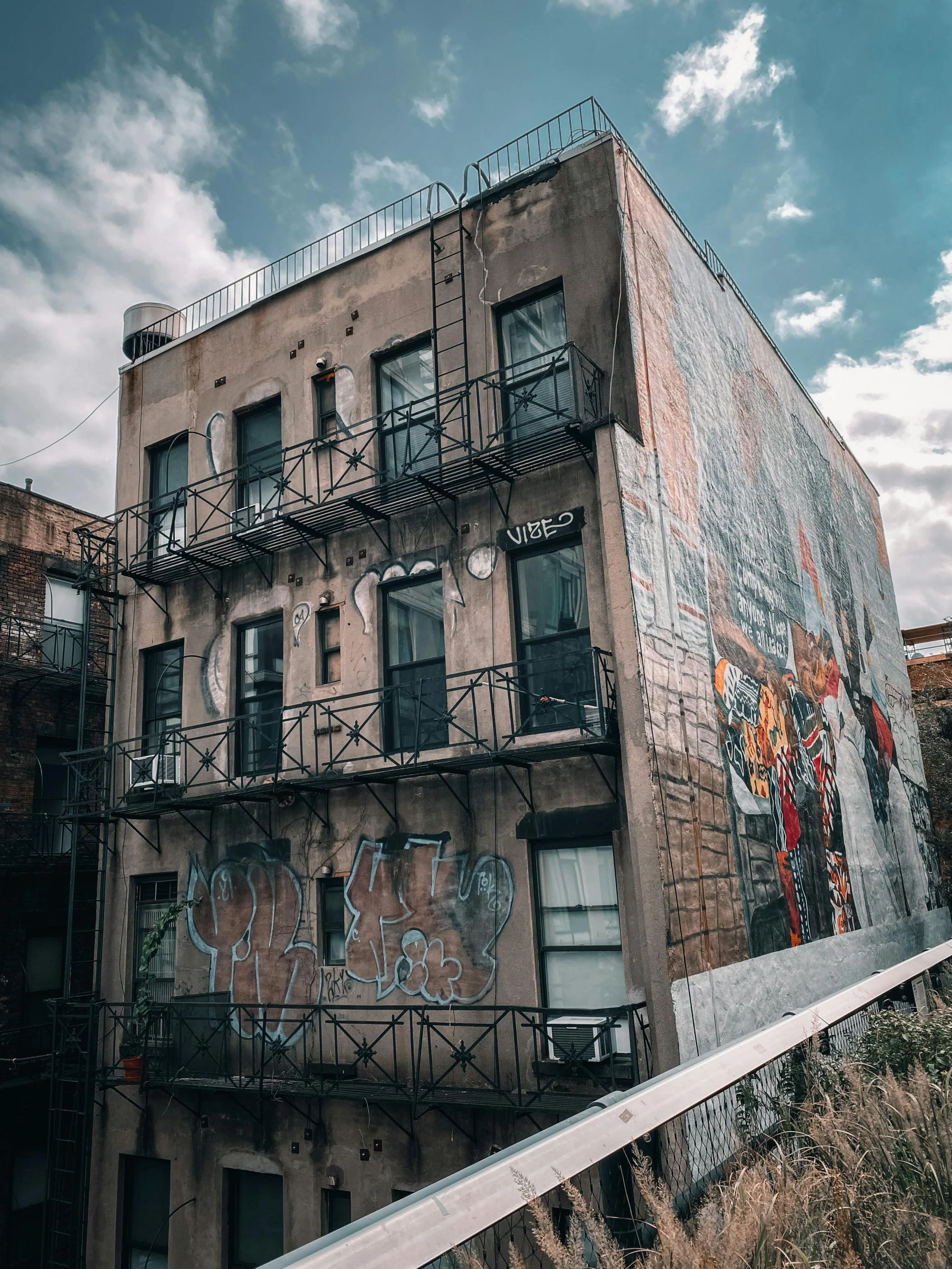 a building with graffiti on the side of it, inspired by Elsa Bleda, pexels contest winner, post apocalyptic new york, crenellated balconies, landscape photo, an escape room in a small