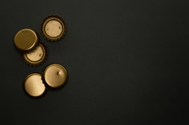 a couple of bottle caps sitting on top of a table, pexels, gold black, plain background, 6 pack, panels