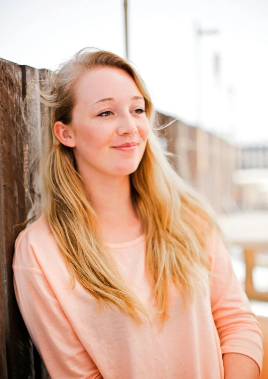 a woman standing in front of a wooden fence, a portrait, inspired by Louisa Matthíasdóttir, unsplash, smiling young woman, halfbody headshot, in 2 0 1 5, programming