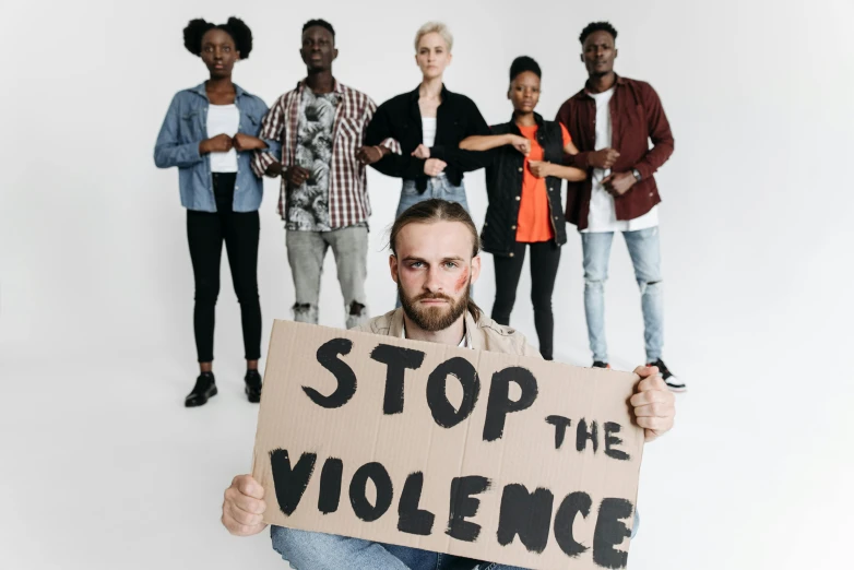 a man holding a sign that says stop the violence, trending on pexels, group photo, profile image, background image, man standing in defensive pose