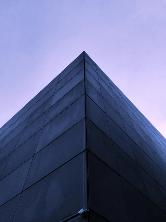 a black building with a blue sky in the background, an album cover, pexels contest winner, modernism, gradient purple, triangle, evening lighting, angular metal