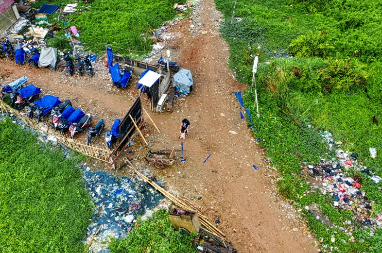 a group of people standing on top of a dirt road, by Daniel Lieske, happening, piles of trash and junk, fpv, flooded fishing village, thumbnail