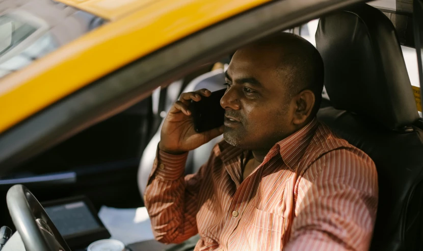 a man sitting in a car talking on a cell phone, pexels contest winner, happening, yellow and charcoal, hindu, large and in charge, dark-skinned