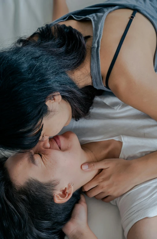 a woman laying on top of a bed next to a man, trending on unsplash, lesbian kiss, asian, neck zoomed in from lips down, gif