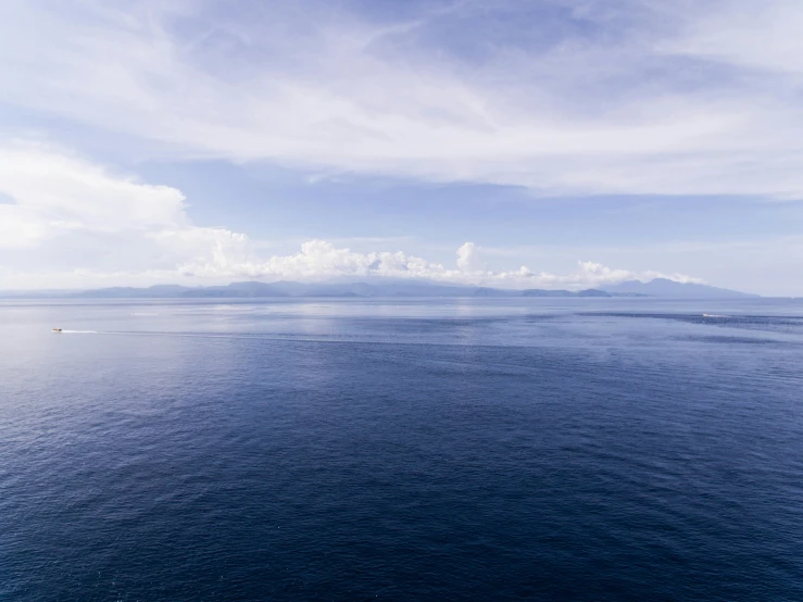 a large body of water with a mountain in the distance, unsplash, minimalism, mariana trench, indonesia, atmospheric photo, big sky