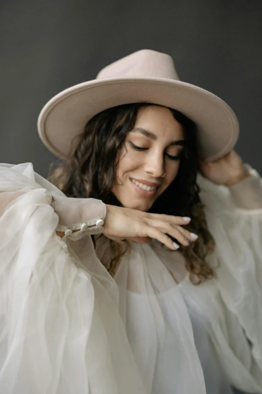 a woman wearing a white dress and a pink hat, an album cover, inspired by Anita Malfatti, trending on pexels, soft smile, hands on face, boho neutral colors, young middle eastern woman